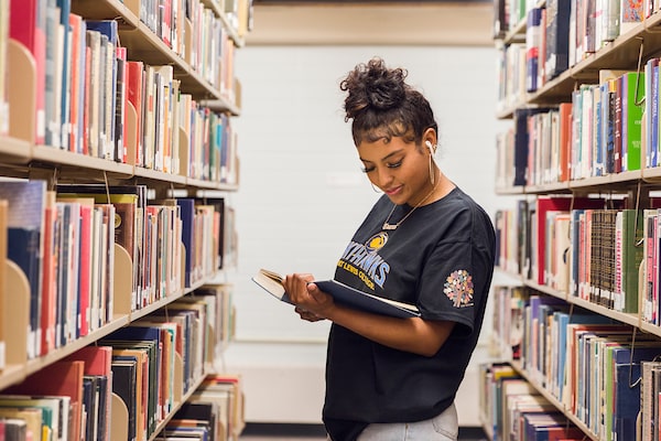 A Fort Lewis College student reads amidst a row of books at the Reed Library.