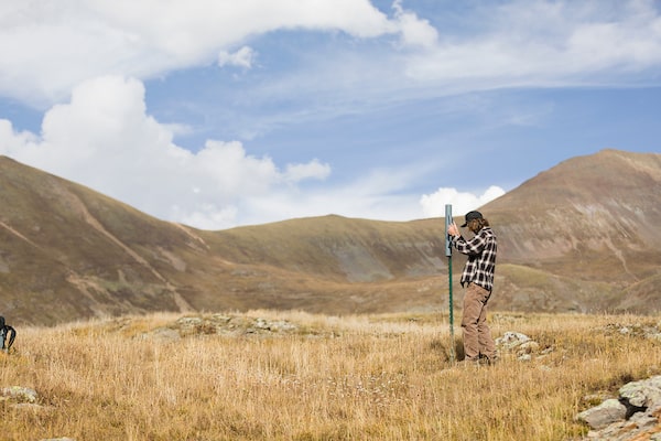 A student intern takes soil samples in the mountains