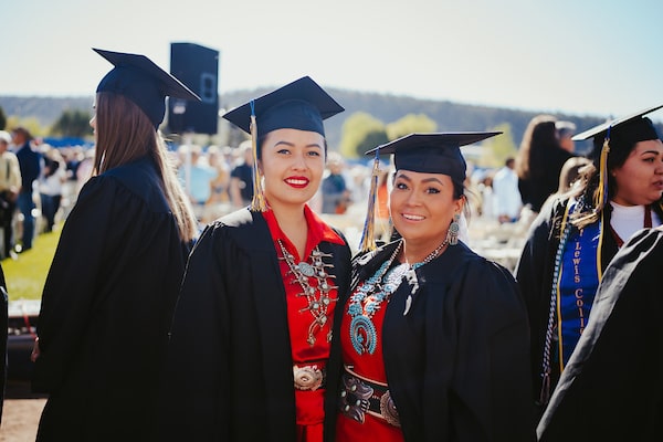 Two Native American business students on graduation day in their caps and gowns.