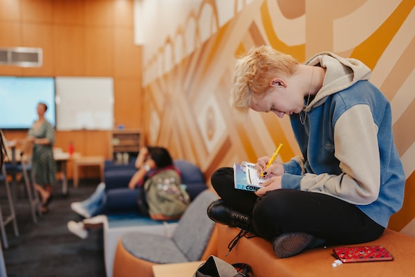 A student writes notes in the Academic Hub